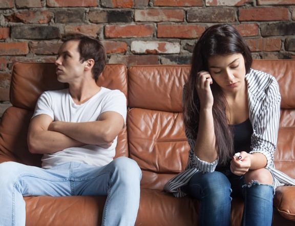 Man and woman sat on couch not speaking to each other